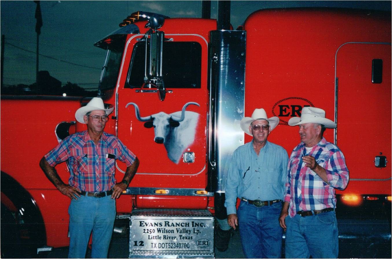 Three men in hats beside the red Evans Ranch truck with the longhorn on its door.