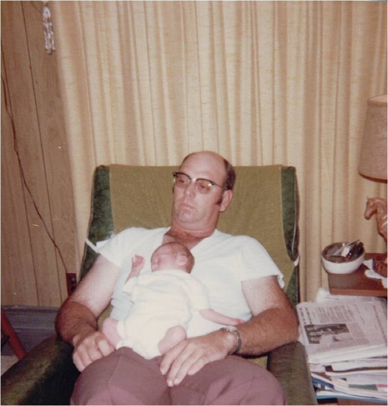 A man asleep in an armchair with a newborn on his chest.